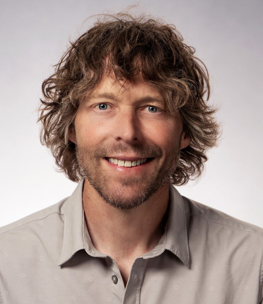 M. Hemenway headshot, beige shirt with light gray background 