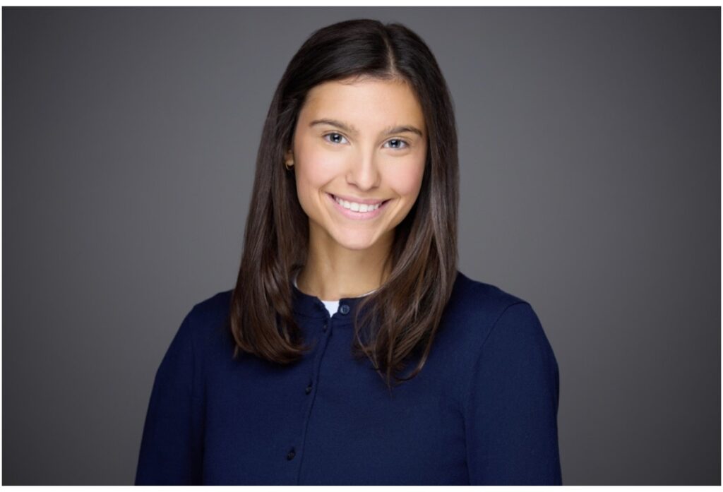 Lia Hayduk headshot, navy blue shirt, standing in front of dark gray background.