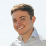 Hudson Patterson headshot, wearing white shirt, standing in front of white background.