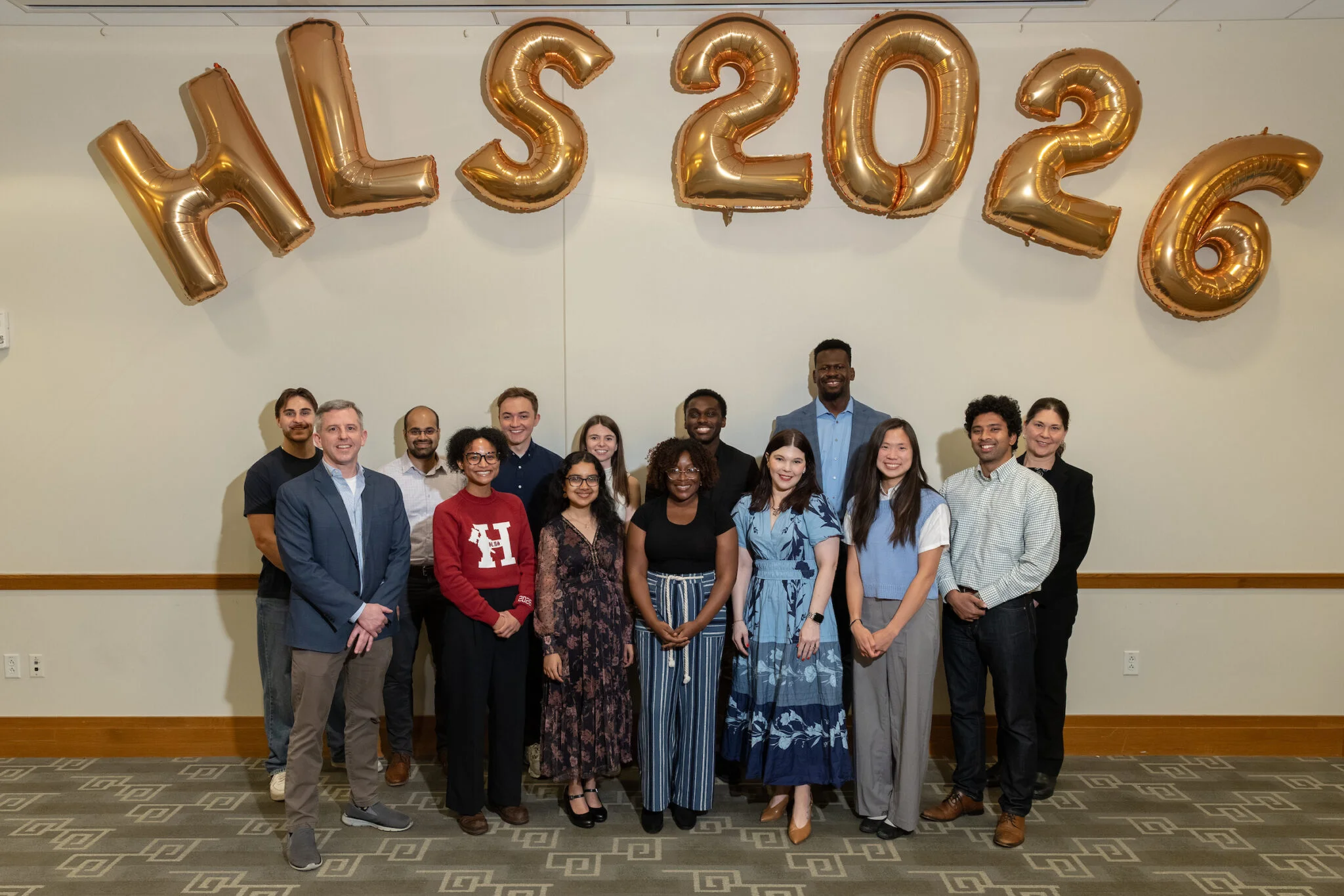 Y-Lab Fellows group photo in front of white wall with gold HLS 2026 balloons.