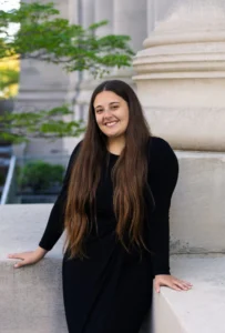 Tabitha Escalante in black dress standing in front of gray column.