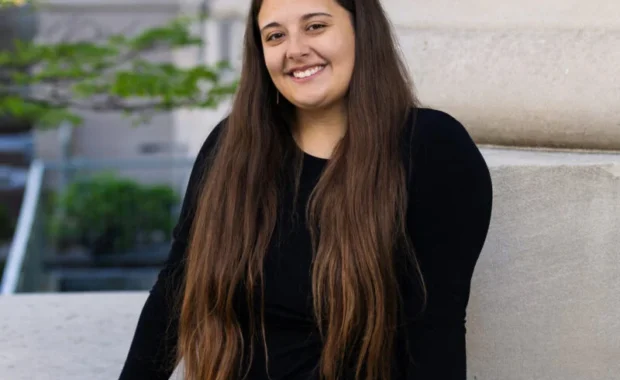 Tabitha Escalante in black dress standing in front of gray column.