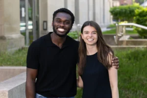 Cordy McJunkins in a black t-shirt and Wesley Streicher in a black t-shirt standing in front of HLS building.