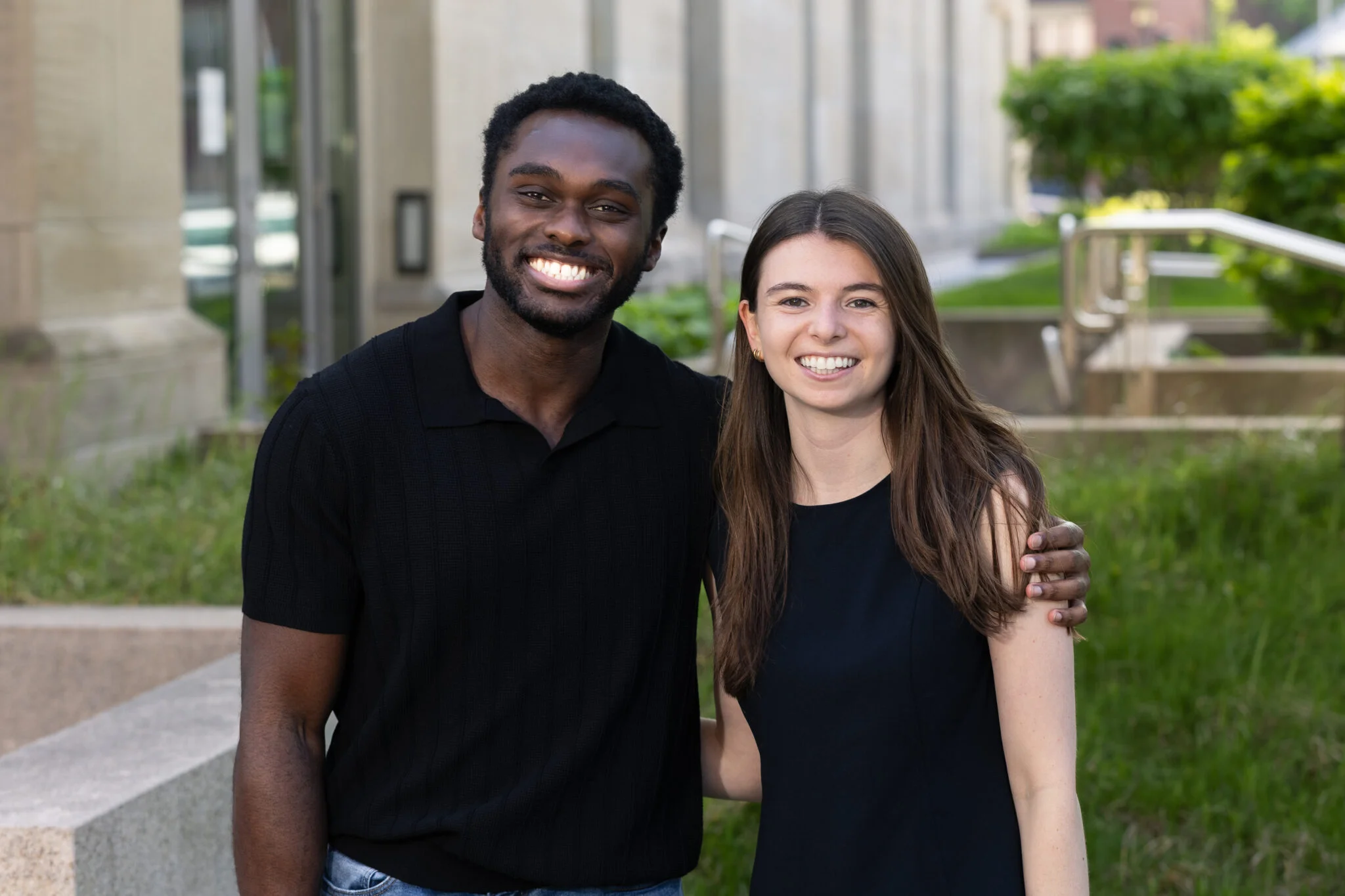 Cordy McJunkins in a black t-shirt and Wesley Streicher in a black t-shirt standing in front of HLS building.